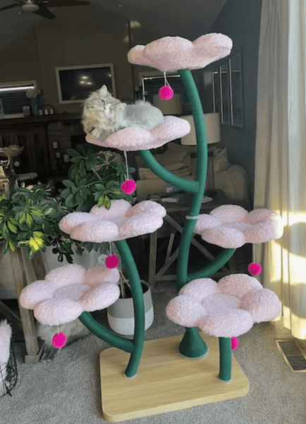 A stylish cat tree with flower-like platforms stands in a modern living room. Soft lighting and pastel décor create a cozy atmosphere.